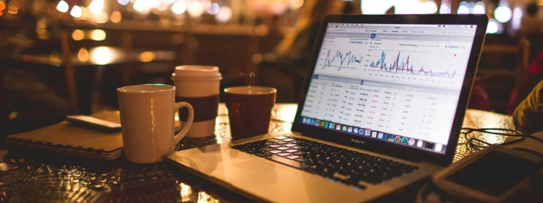 a laptop displaying detailed seo analytics charts and graphs, surrounded by coffee cups and notebooks on a sleek desk.